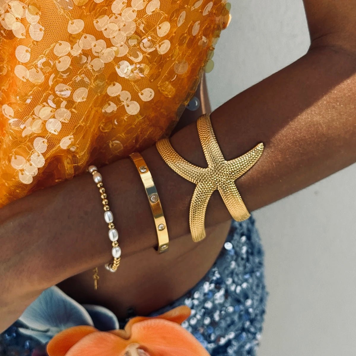 Starfish cuff bracelet styled with gold and pearl jewelry on dark skin