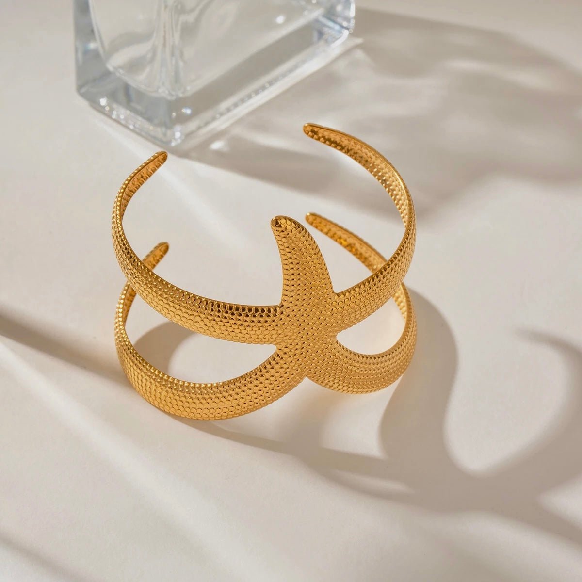 Minimalist flatlay of gold starfish cuff bracelet on a neutral background