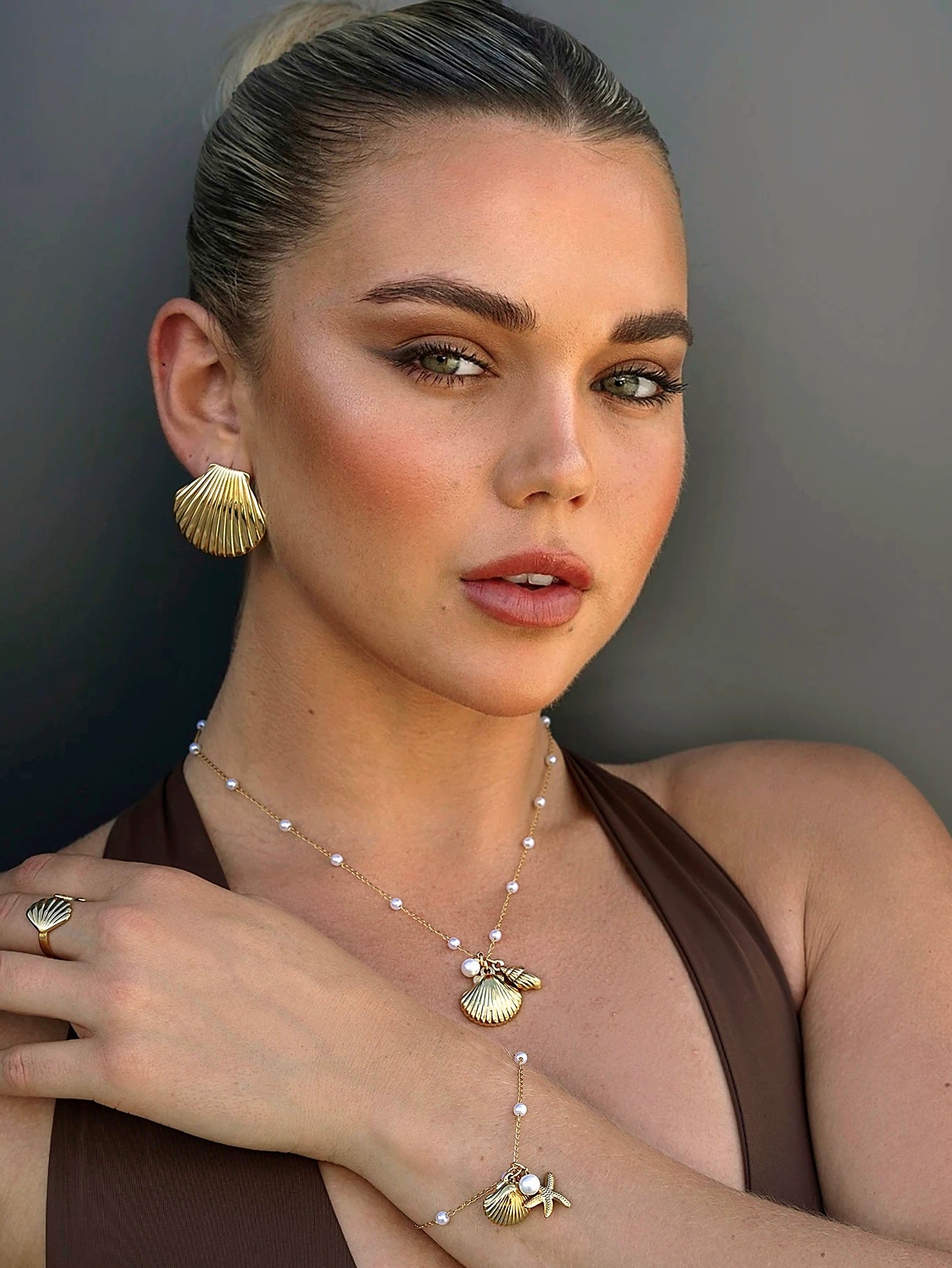 Model wearing matching gold seashell earrings and necklace