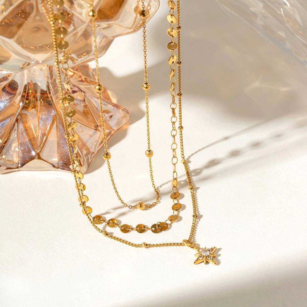 Gold layered necklace with star pendant floating in soft light