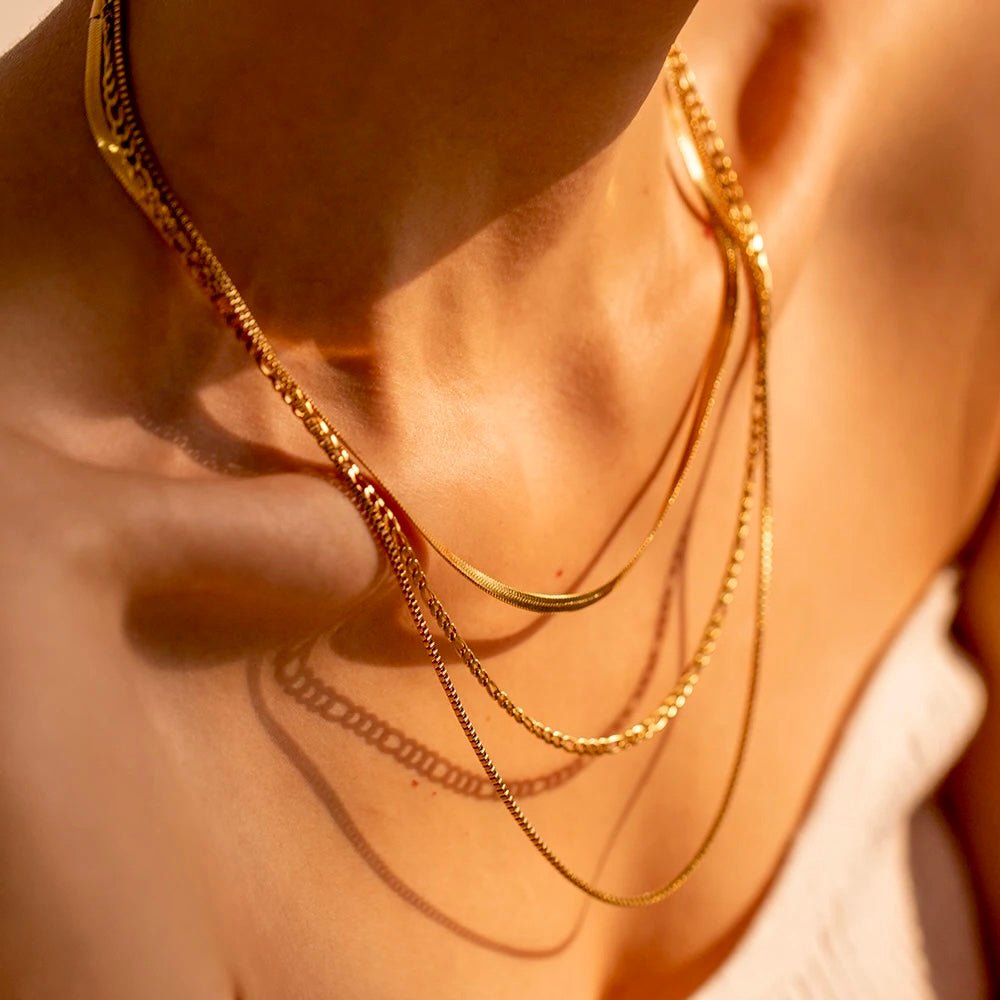 Close-up of 3 gold chains layered under golden light
