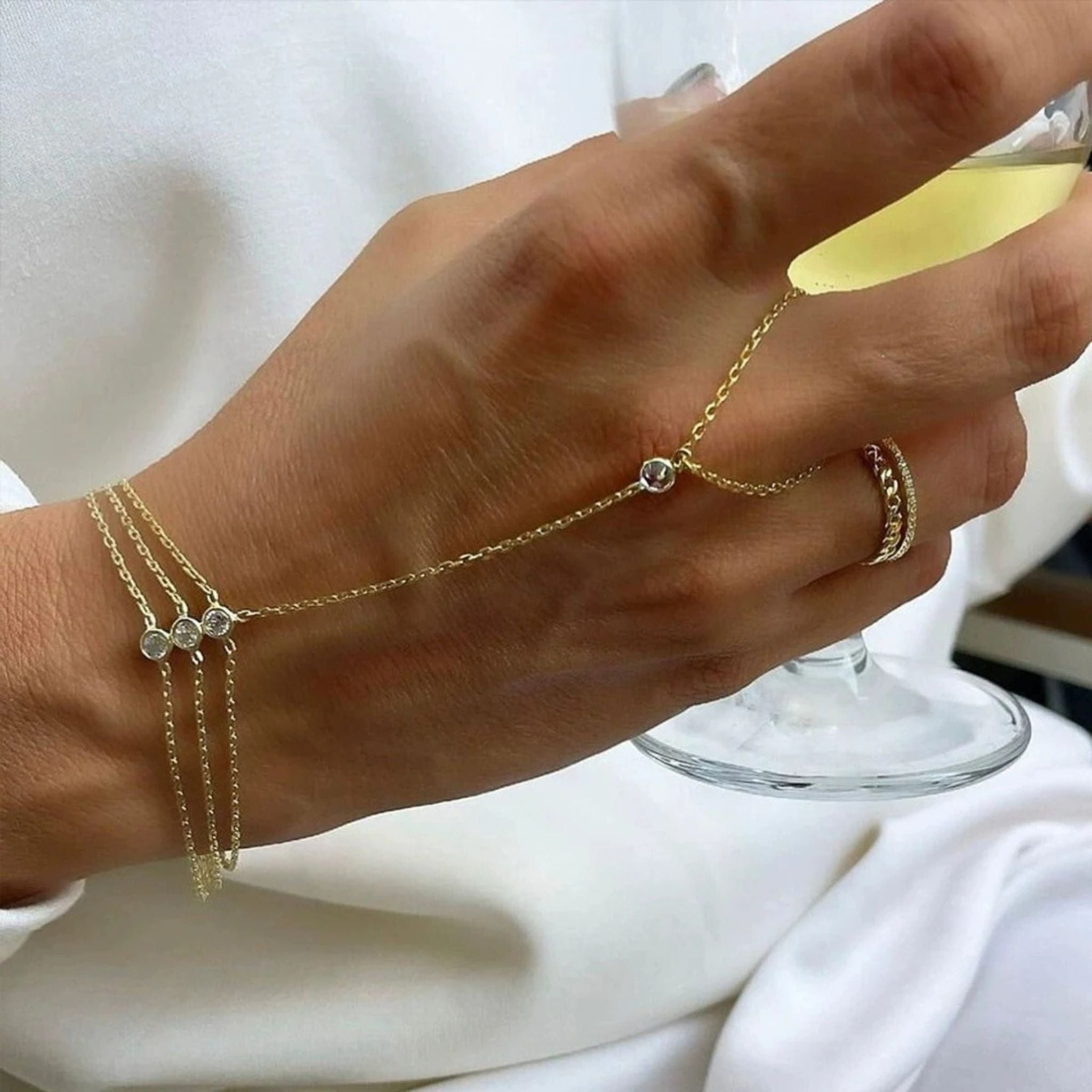 Close-up of the Gold Trio Hand Chain Bracelet worn on the hand, featuring three zircon stones and 18K gold-plated chains.