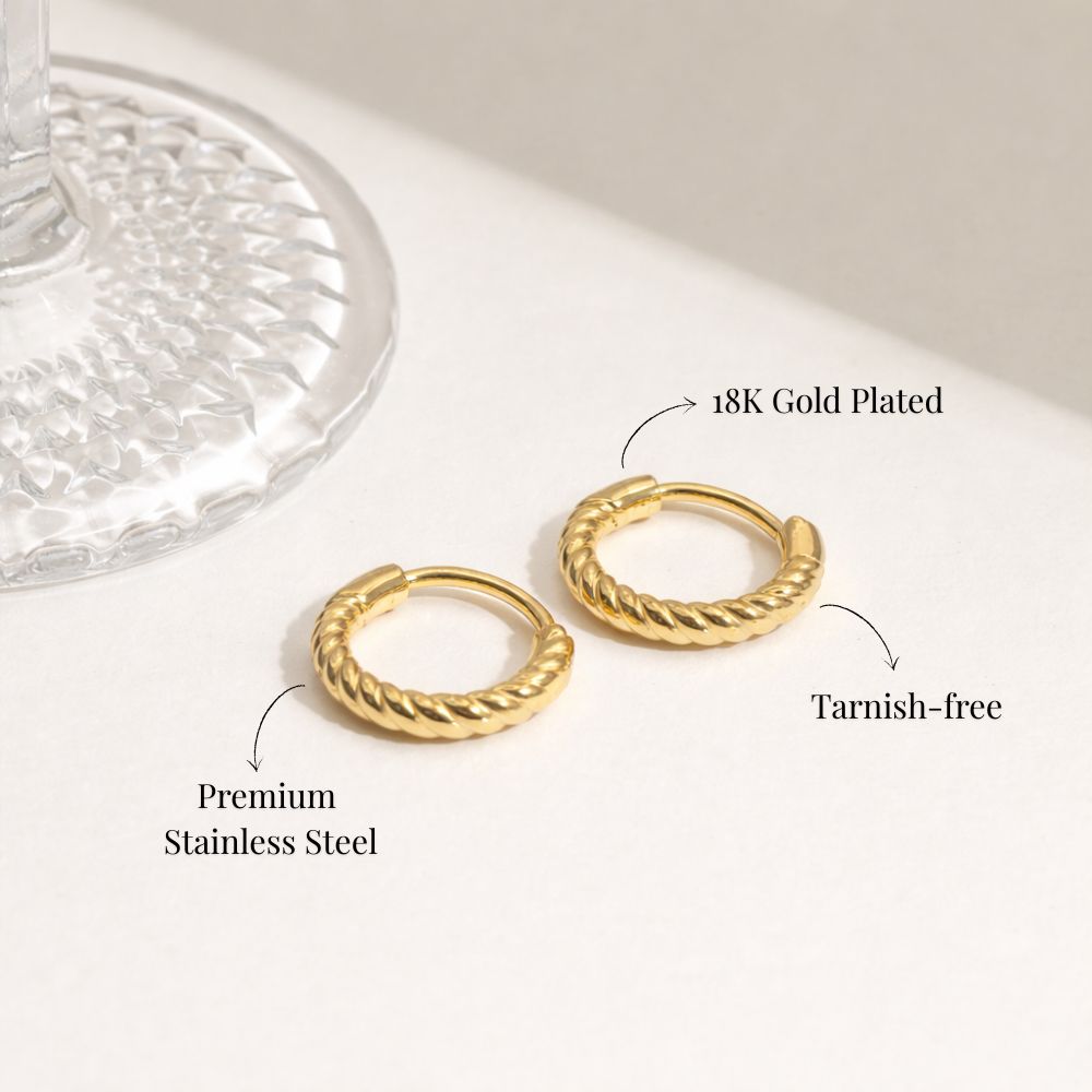 Close-up of gold twisted hoop earrings worn on ear, minimalist rope texture huggie hoops.