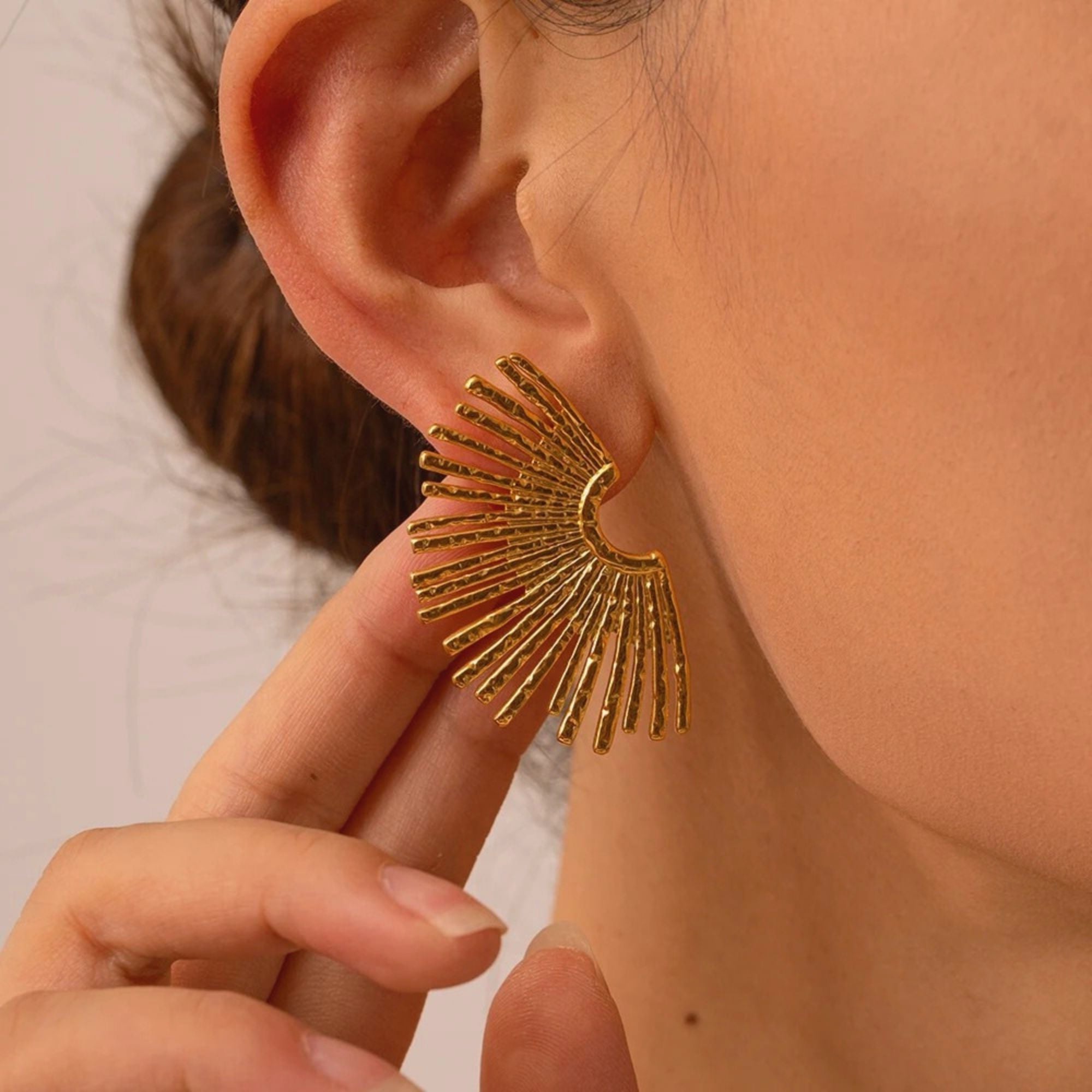 Close-up of hammered gold Golden Halo Earrings with radiant fan silhouette