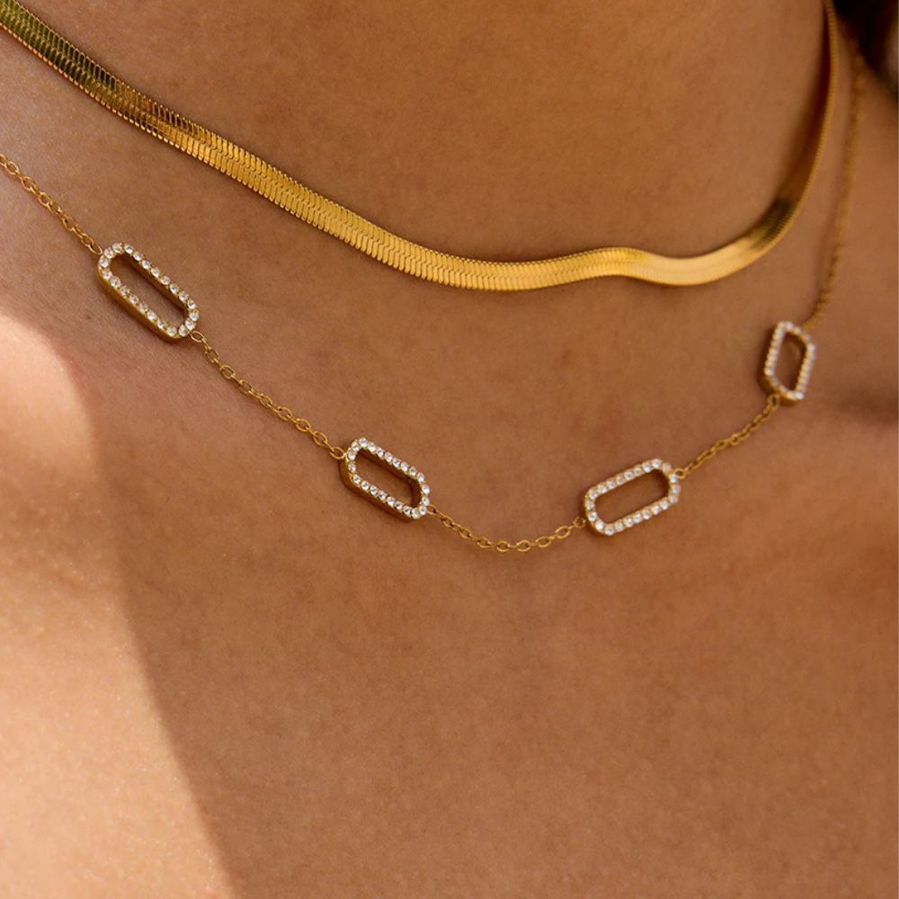 Layered gold necklace set worn with herringbone chain and crystal link necklace