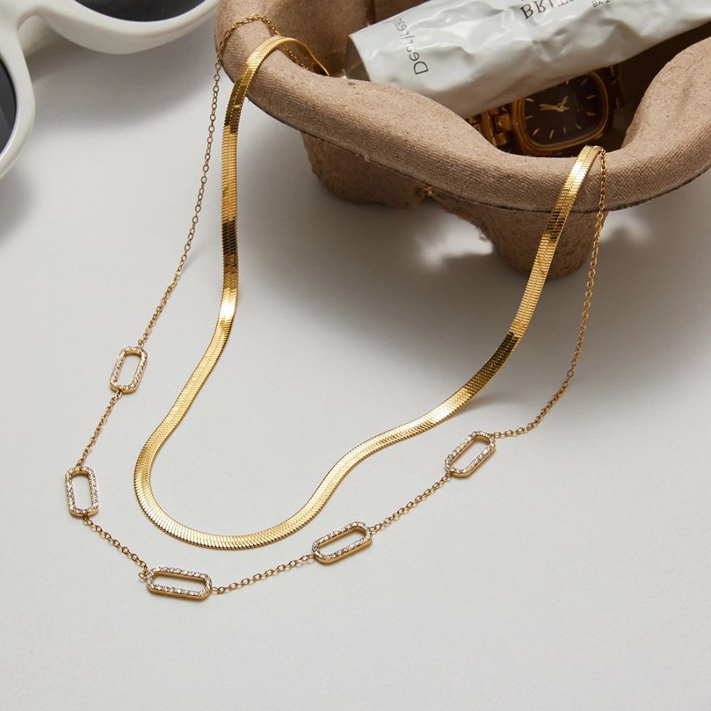Gold layered necklace set styled with herringbone choker and crystal link necklace