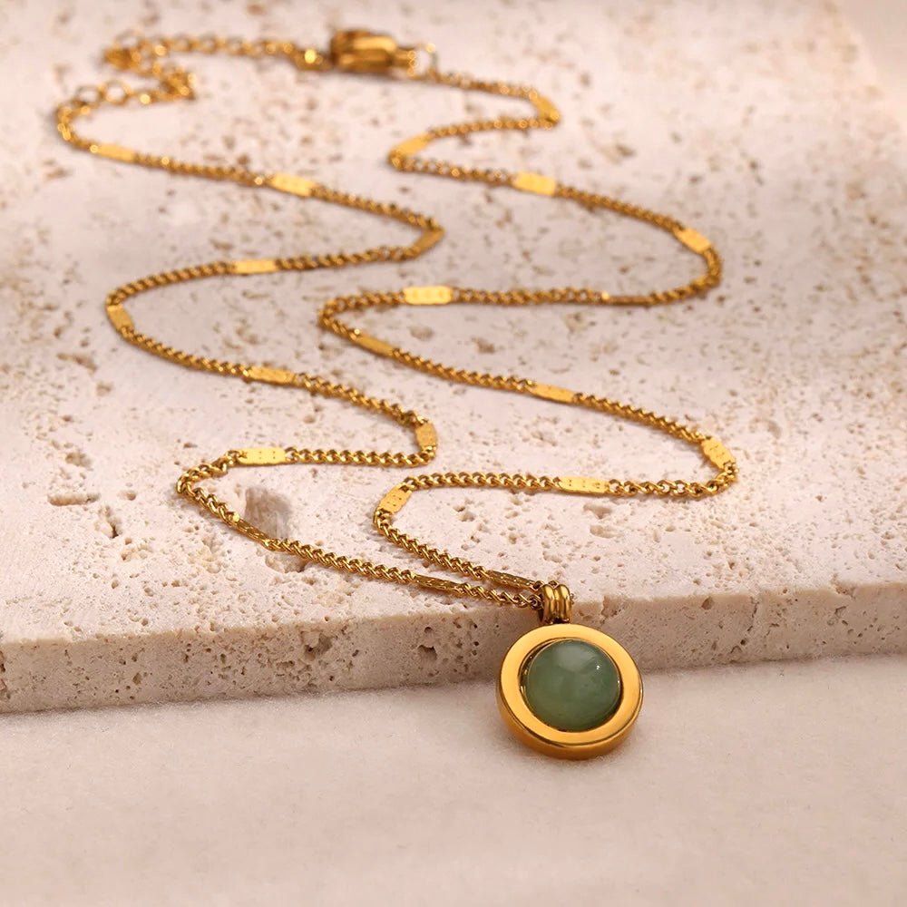 Round green stone pendant in gold bezel setting on flat chain