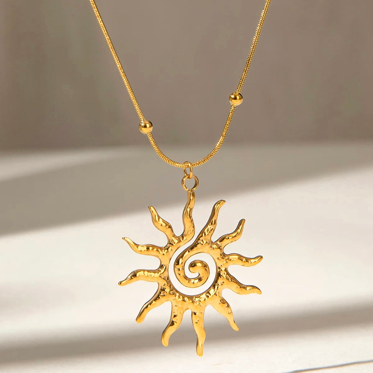 Gold sun necklace with textured finish under natural light
