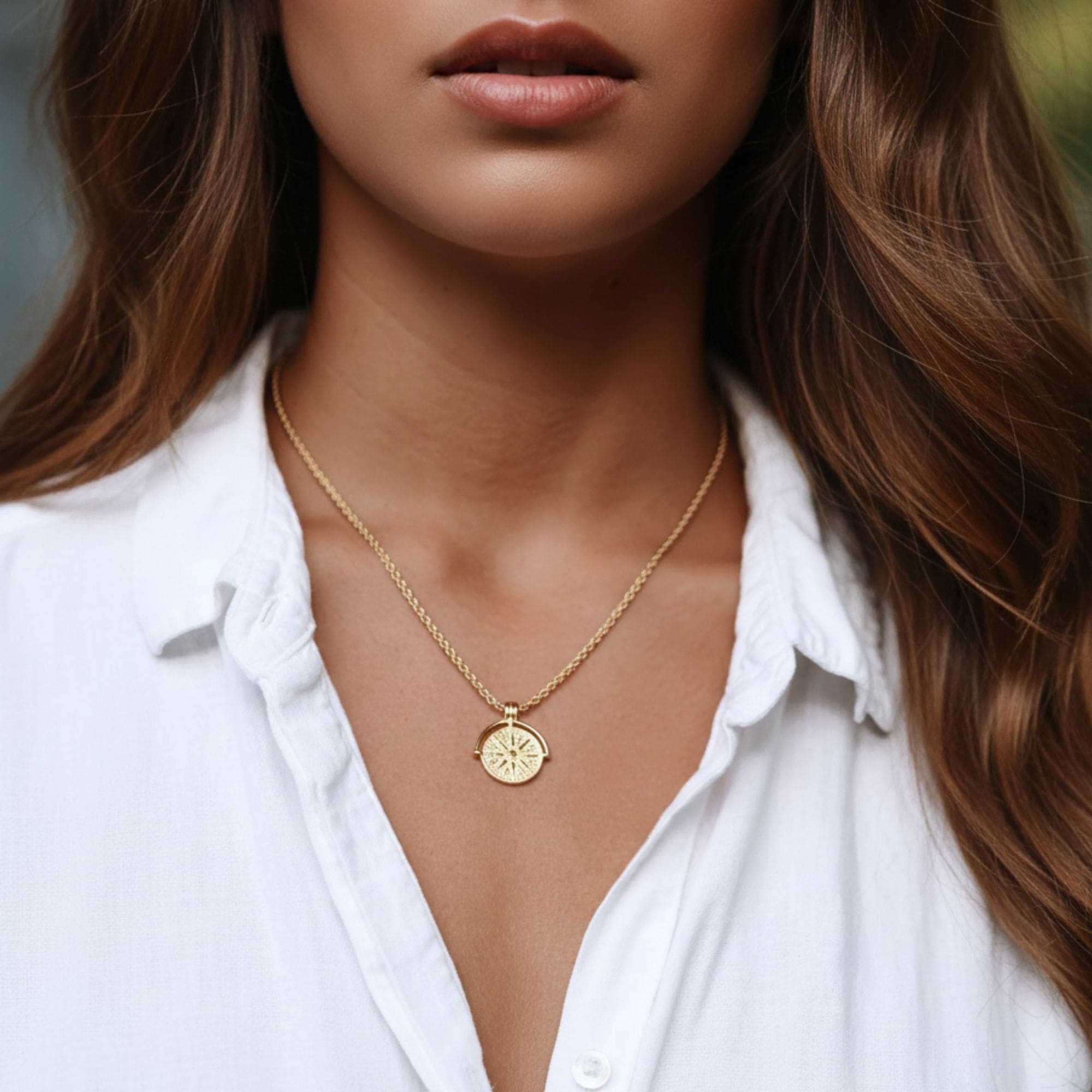 Helia Necklace in gold displayed on seashell with water drop effect.