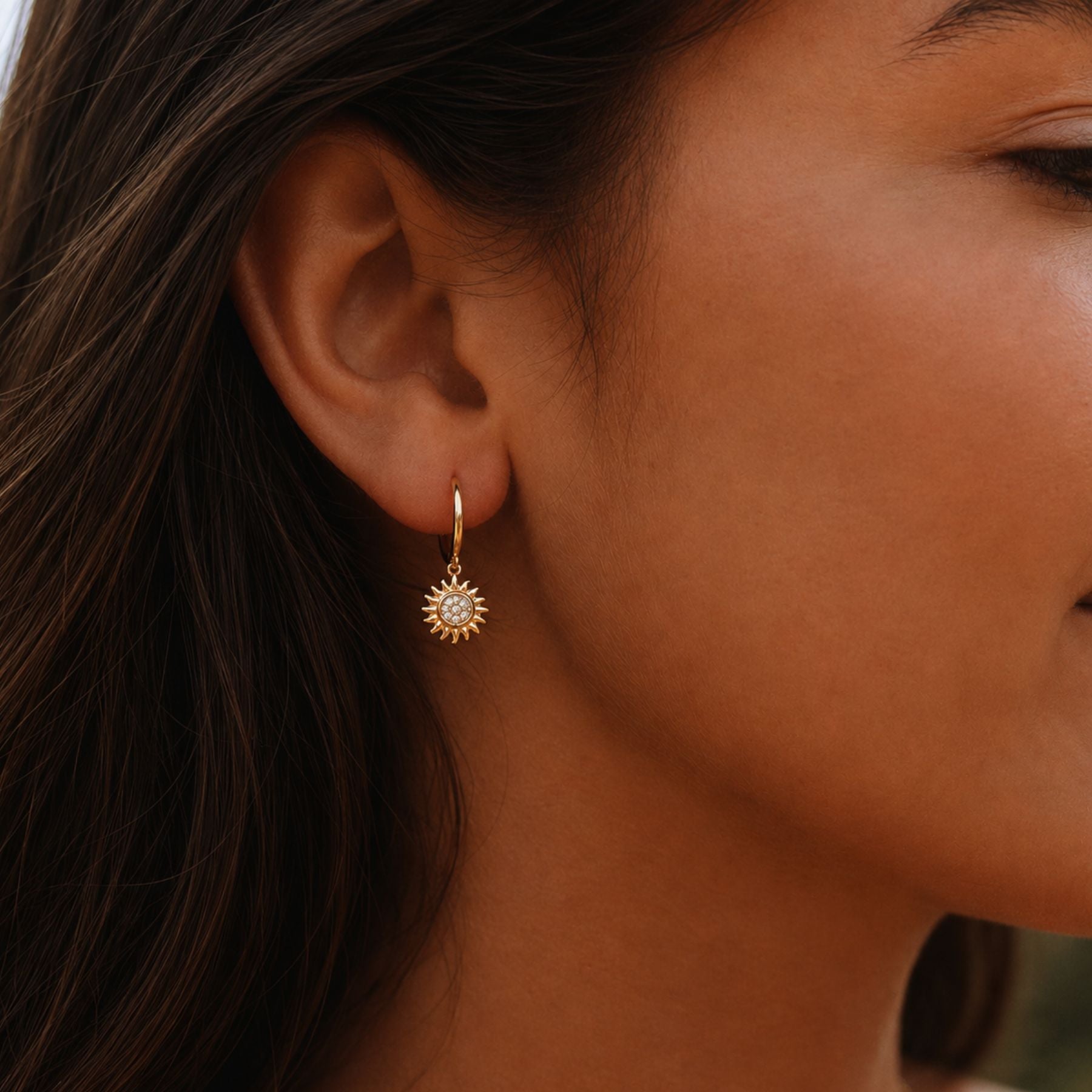 Helio gold sun hoop earrings with sparkling zirconia charm worn on model