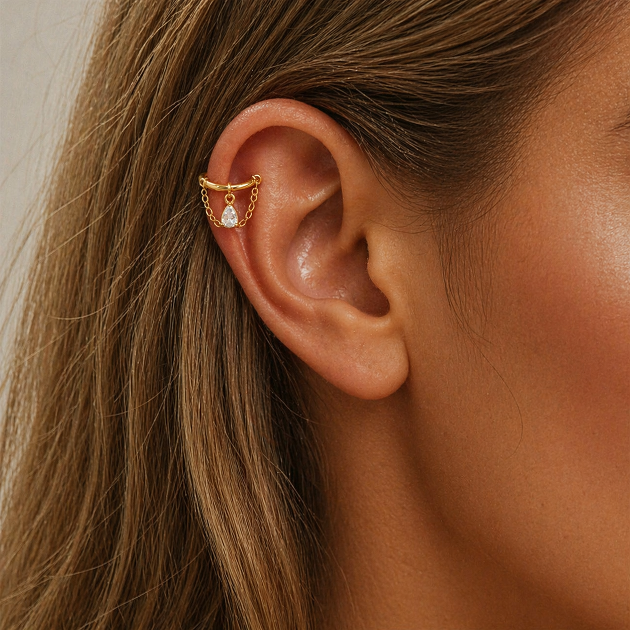 Helix ear cuff chain earring worn on upper ear with teardrop cubic zirconia charm and delicate gold chains, helix piercing jewelry