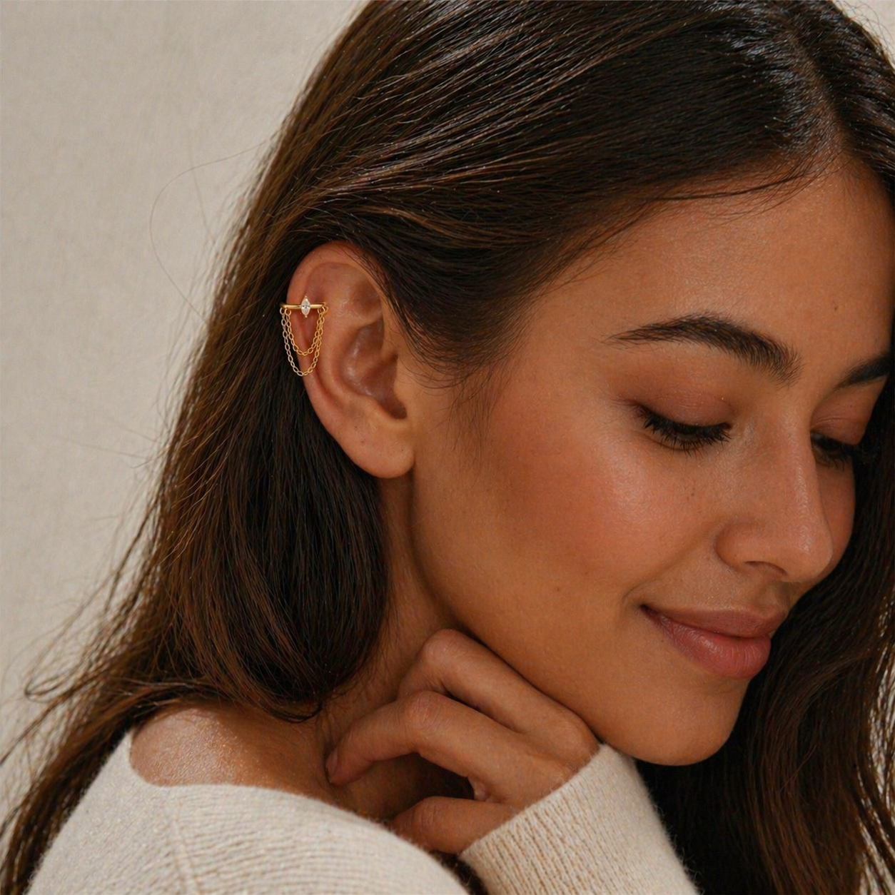 Woman wearing gold helix chain earring with marquise CZ stone and delicate chains, helix piercing jewelry
