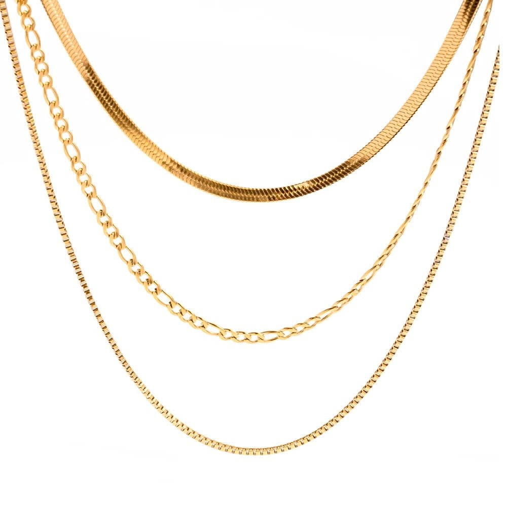 Close-up view of triple-layered gold necklace with snake, figaro, and curb chains