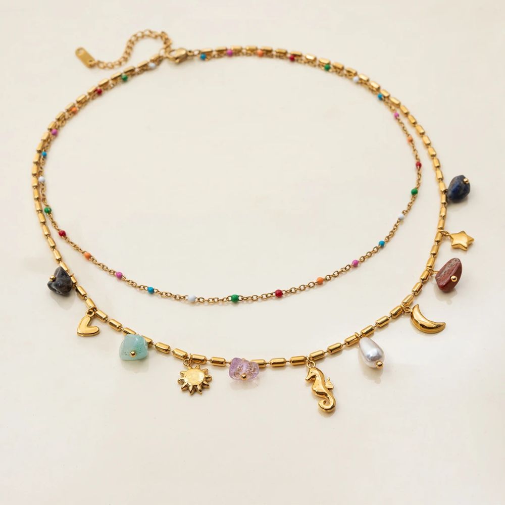 Layered gold necklace with charms and beads product shot on neutral background