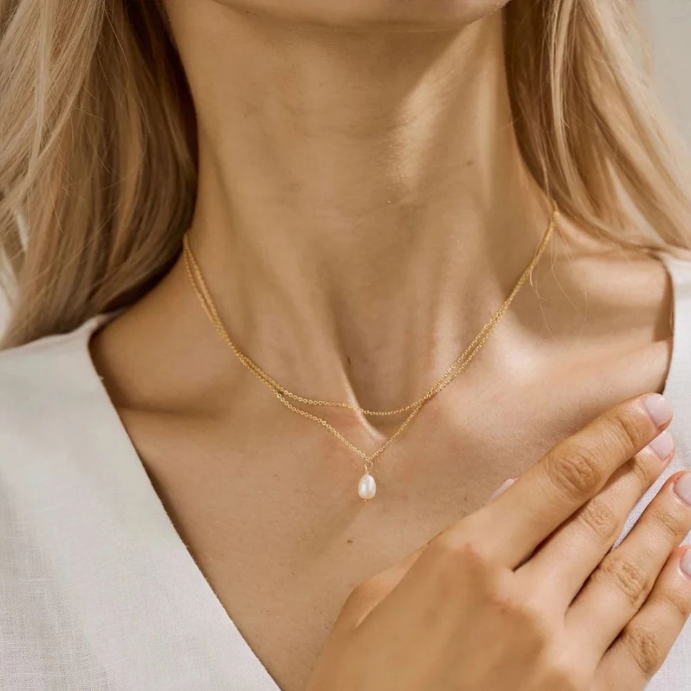  Gold layered freshwater pearl necklace styled on wet skin at the beach.