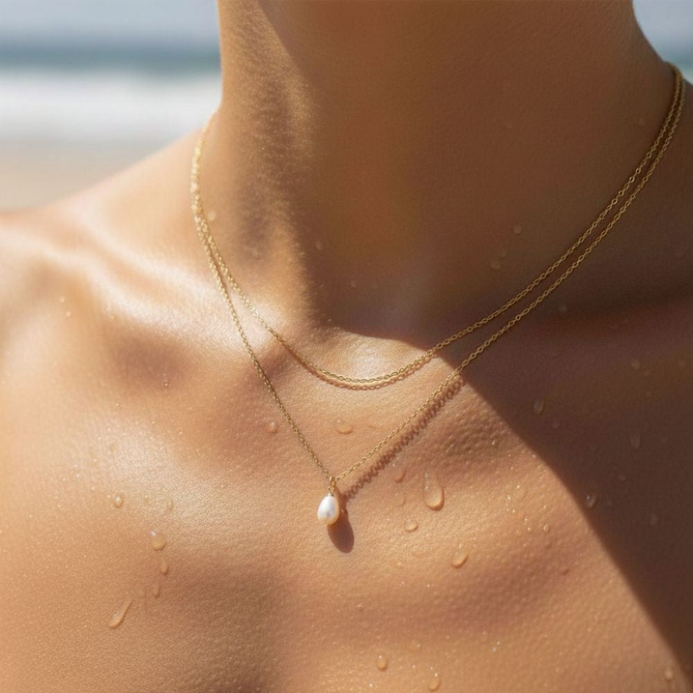  Gold layered freshwater pearl necklace styled on wet skin at the beach.