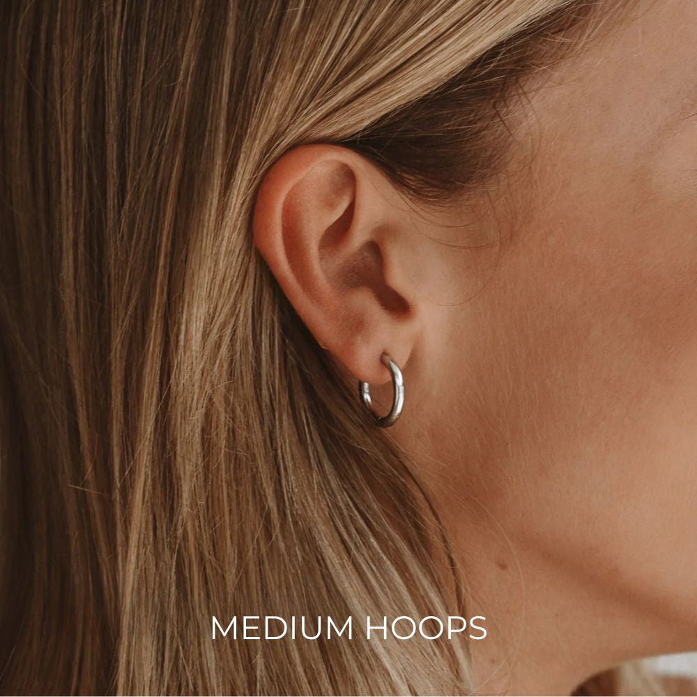 Model wearing medium silver essential hoop earrings, minimalist stainless steel hoops for everyday wear