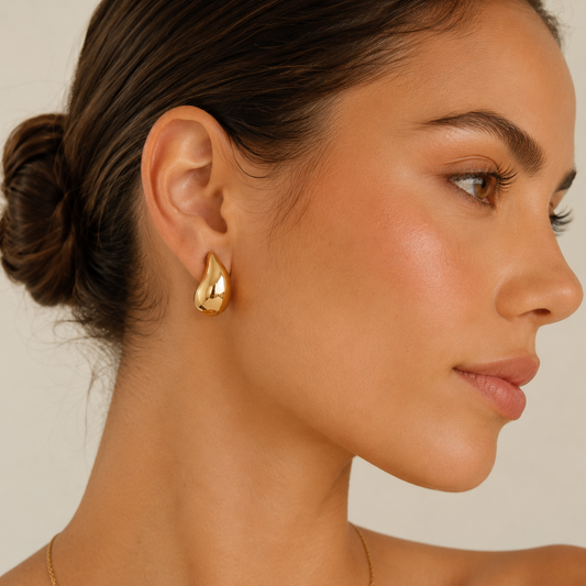Teardrop gold stud earrings on model, minimalist statement earrings in 18K gold plated stainless steel