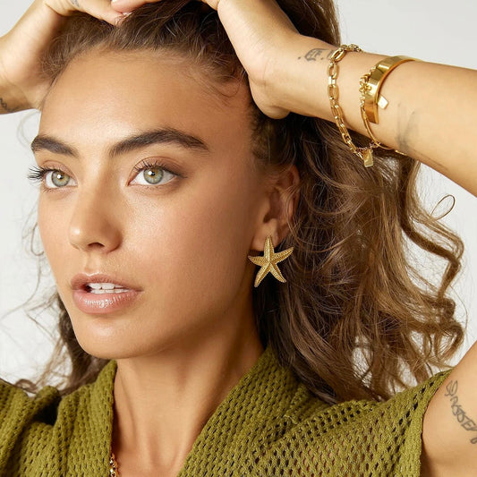 Woman wearing gold starfish earring, side profile view for summer jewelry inspiration