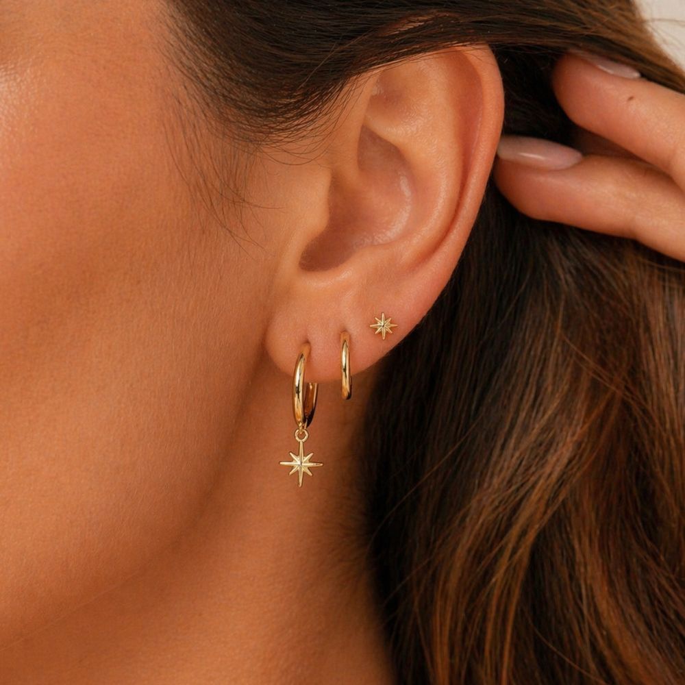 North star earrings set in gold worn as ear stack on lobe piercings, waterproof stainless steel hoop and stud earrings