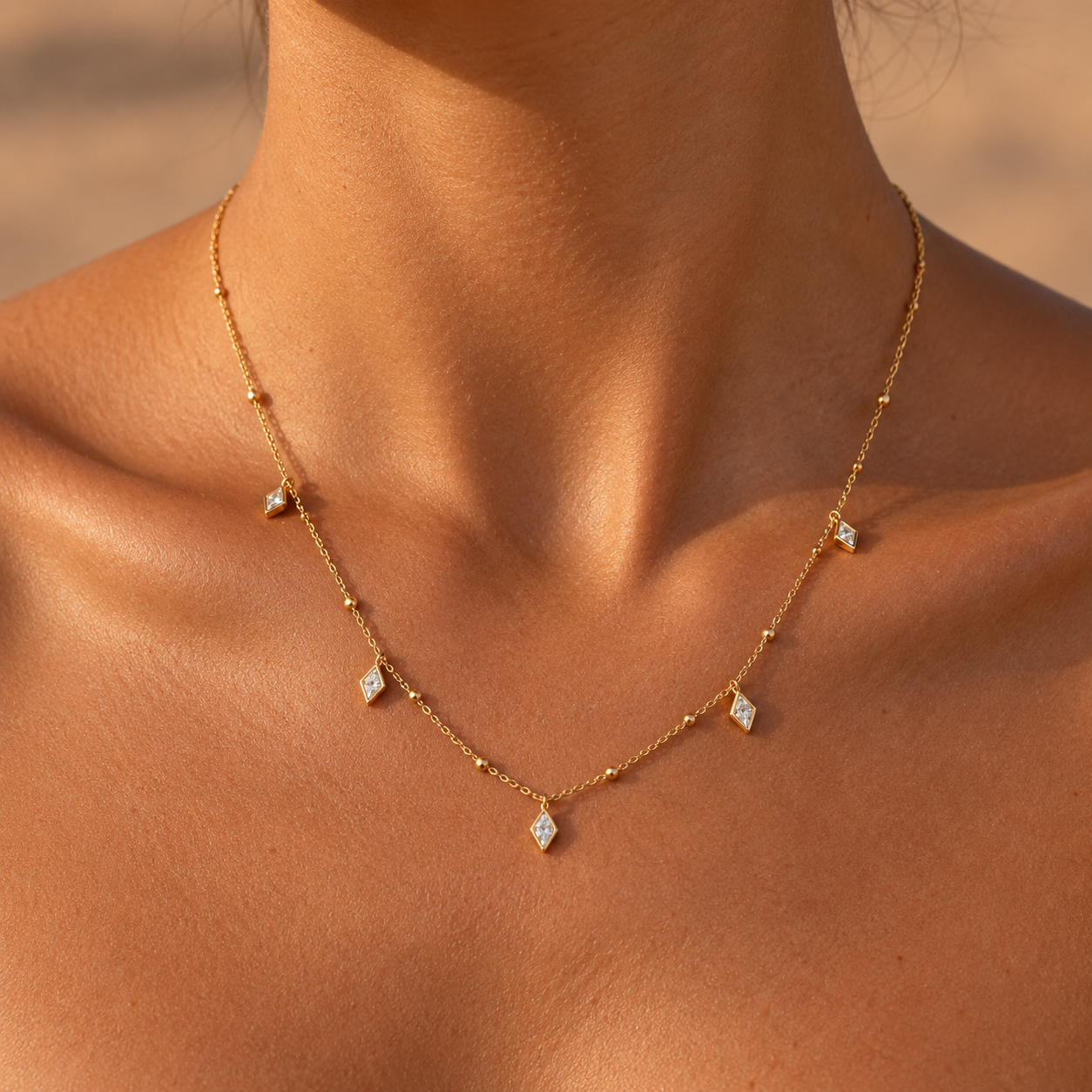 Woman wearing a dainty gold satellite chain necklace with diamond-shaped CZ charms, 18K gold plated waterproof necklace