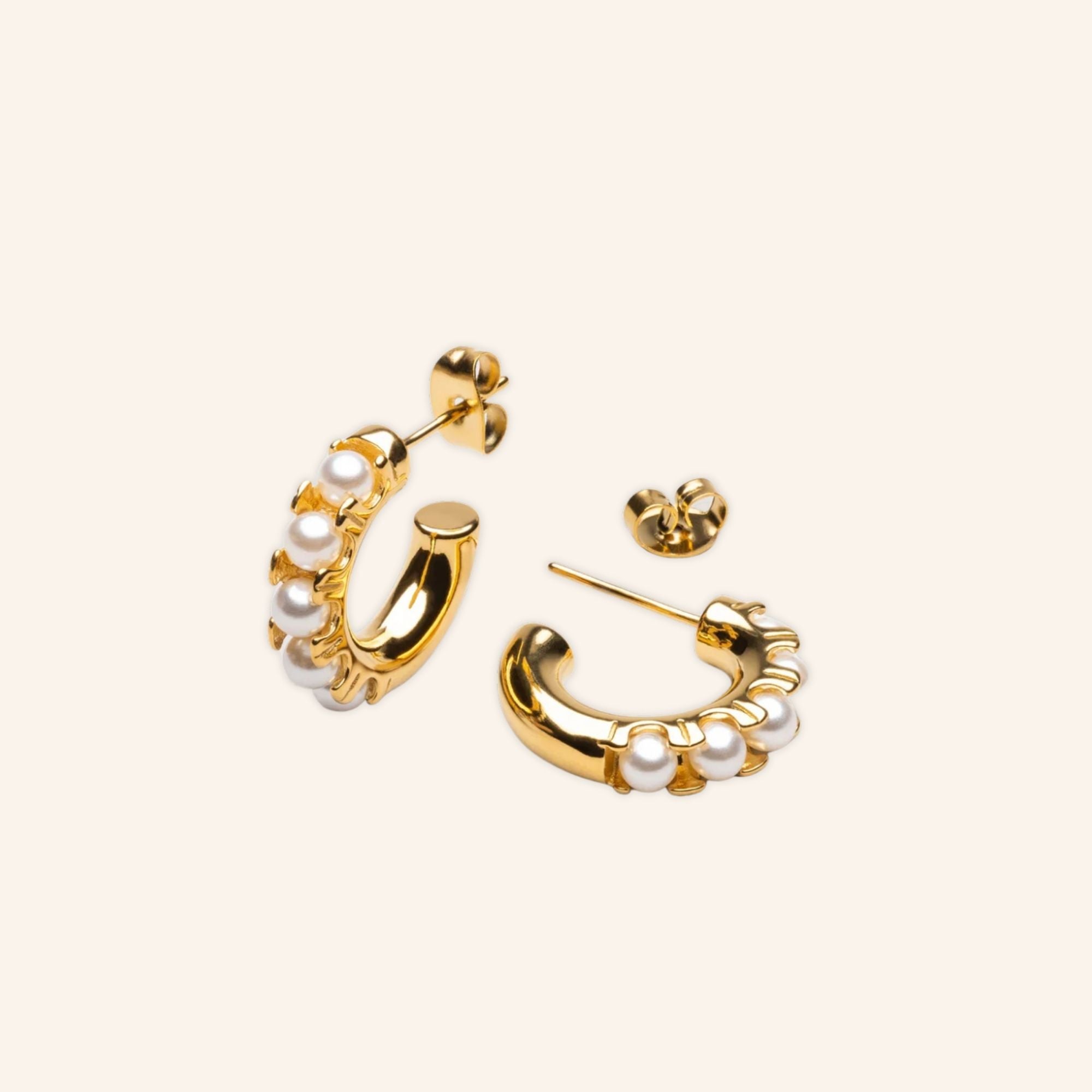 Pair of gold pearl huggie earrings on neutral background, 18K gold-plated stainless steel with freshwater pearls