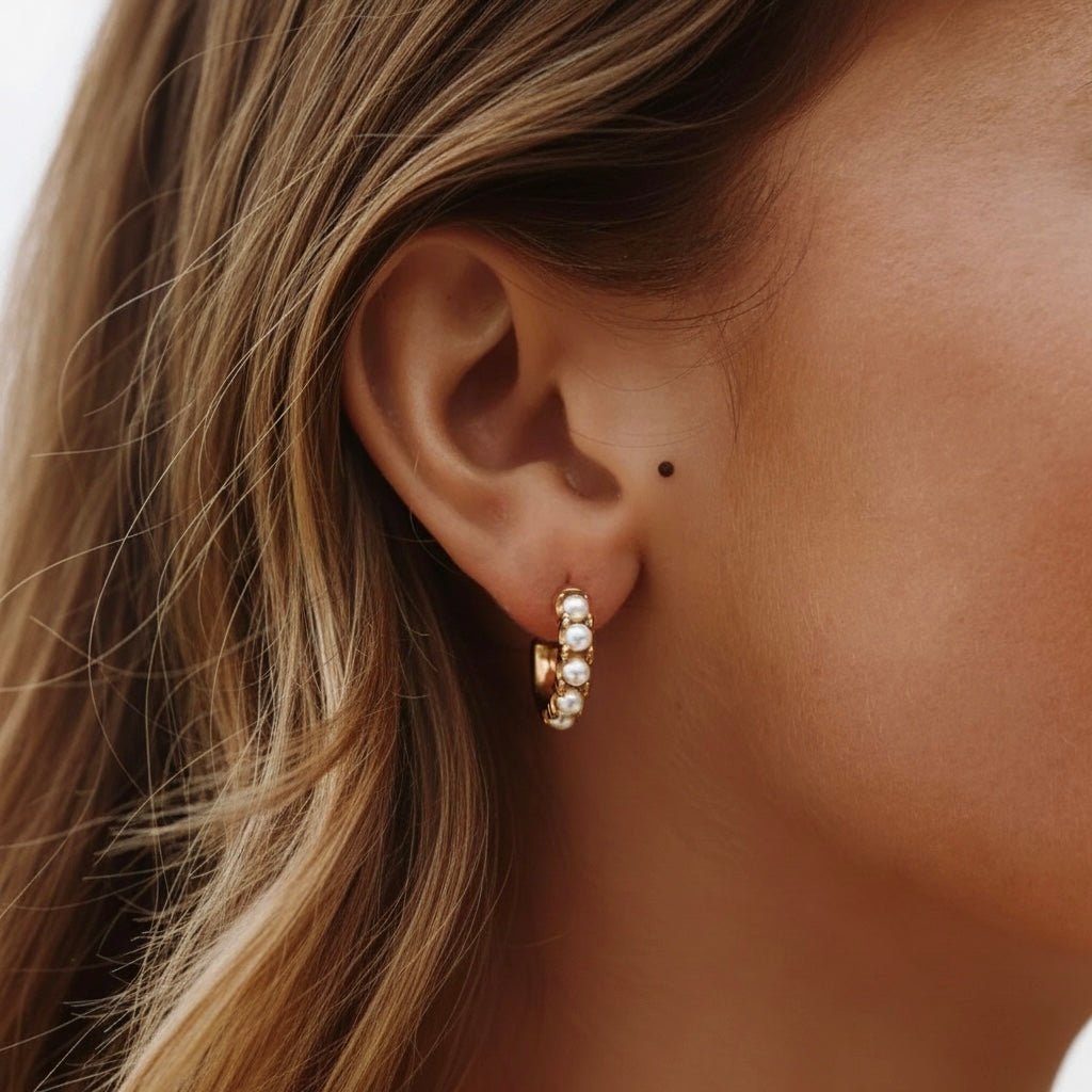 Model wearing gold pearl huggie earrings, small 18K gold-plated hoops with freshwater pearls.