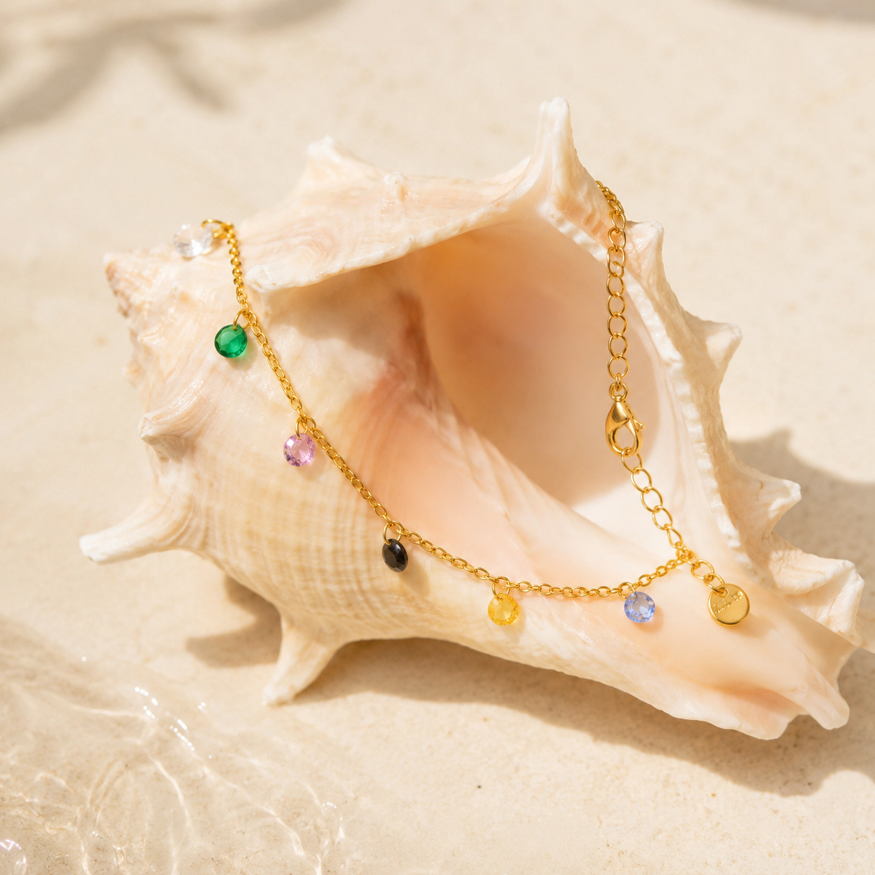 Rainbow Anklet with multicolor cubic zirconia charms displayed on a seashell, waterproof gold anklet beach jewelry.