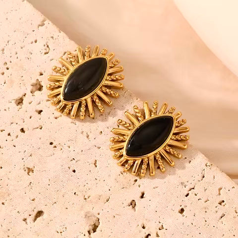 Woman wearing bold sunburst marquise black and gold earrings – side profile