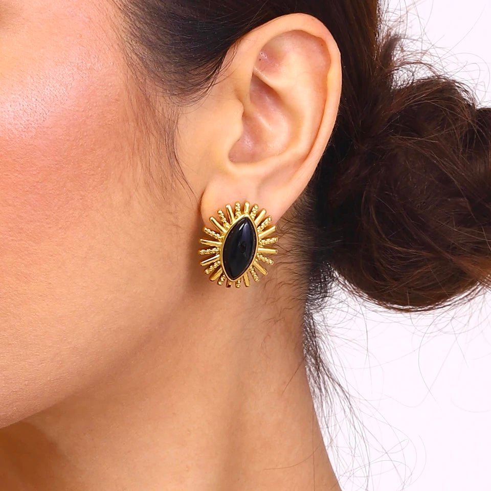 Woman wearing bold sunburst marquise black and gold earrings – side profile