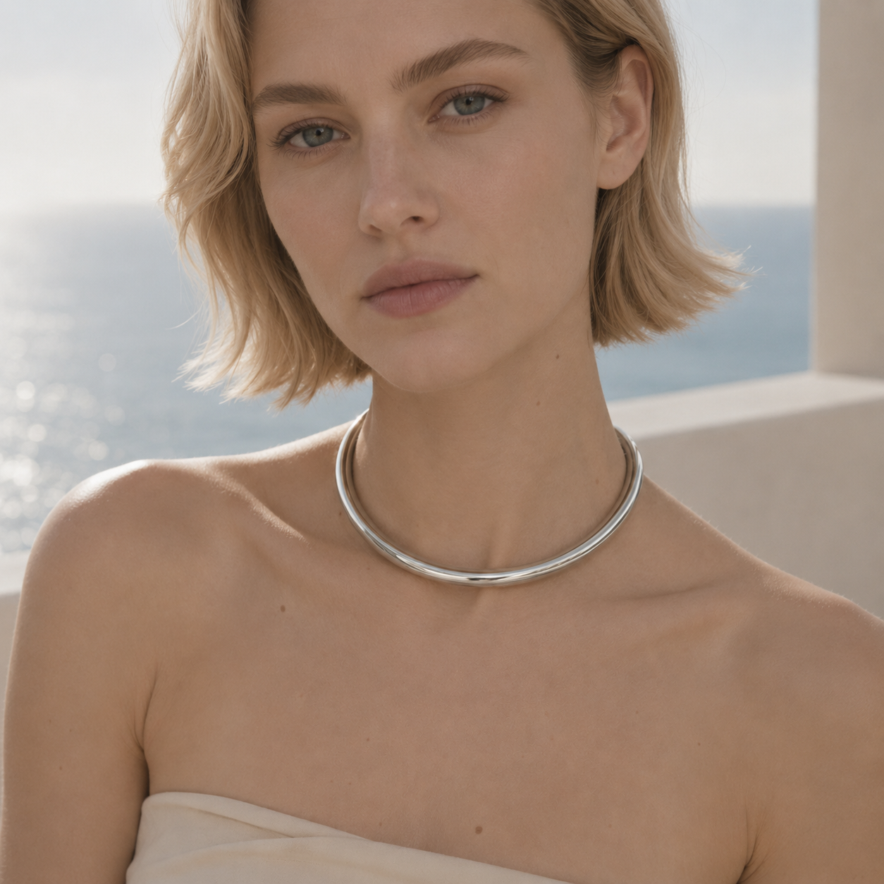 Woman wearing a silver collar necklace by the ocean