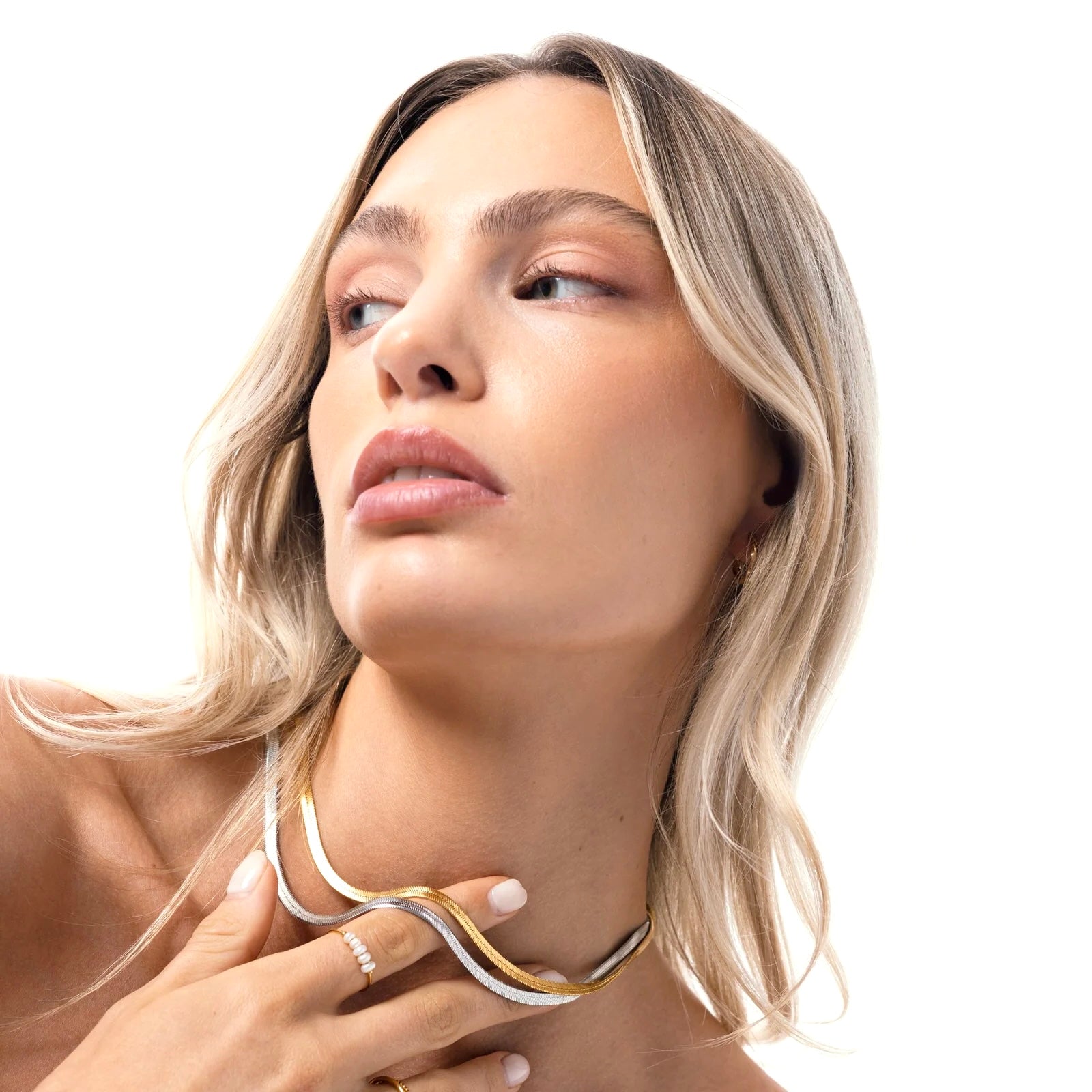 Layered silver and gold snake chain necklaces on model