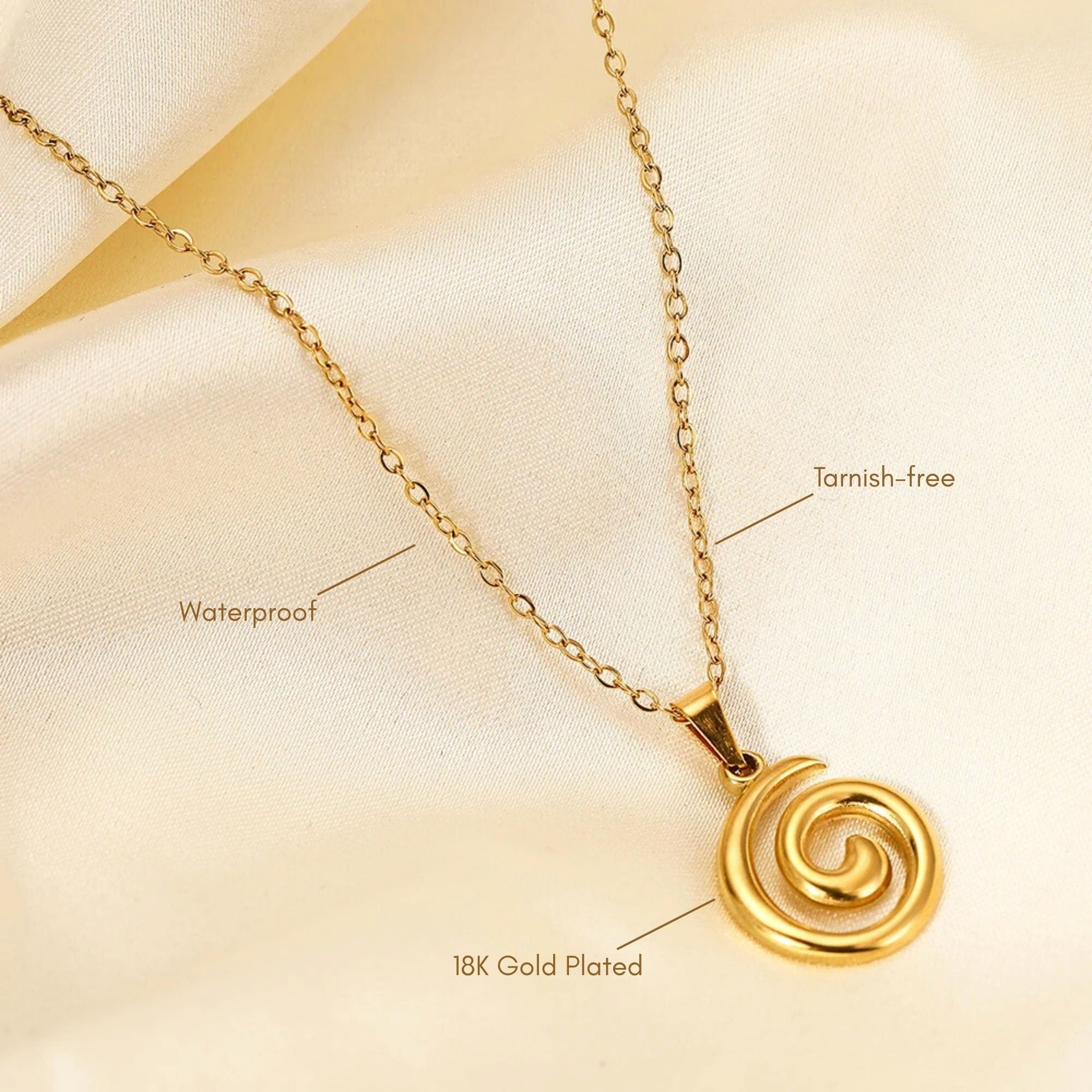 Gold spiral necklace on satin fabric showing waterproof and tarnish-free 18K gold plating