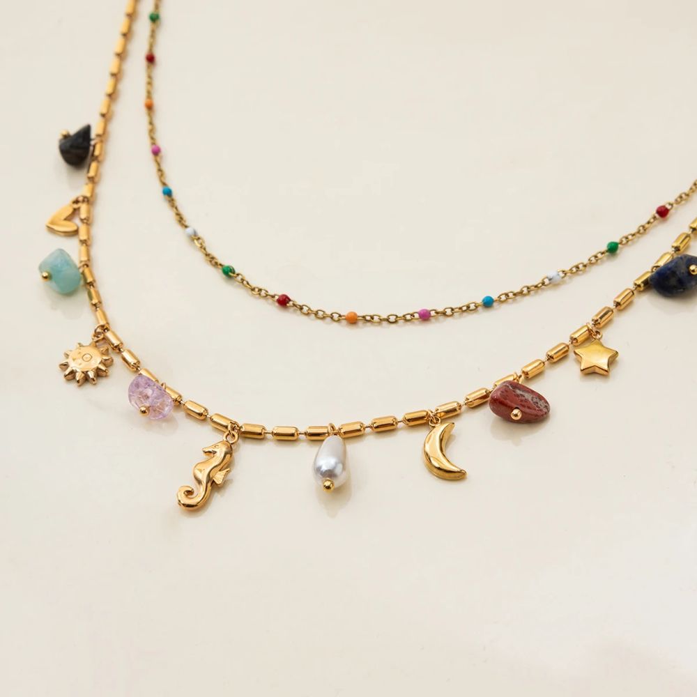 Close-up of summer layered gold necklace with charms and bead chain