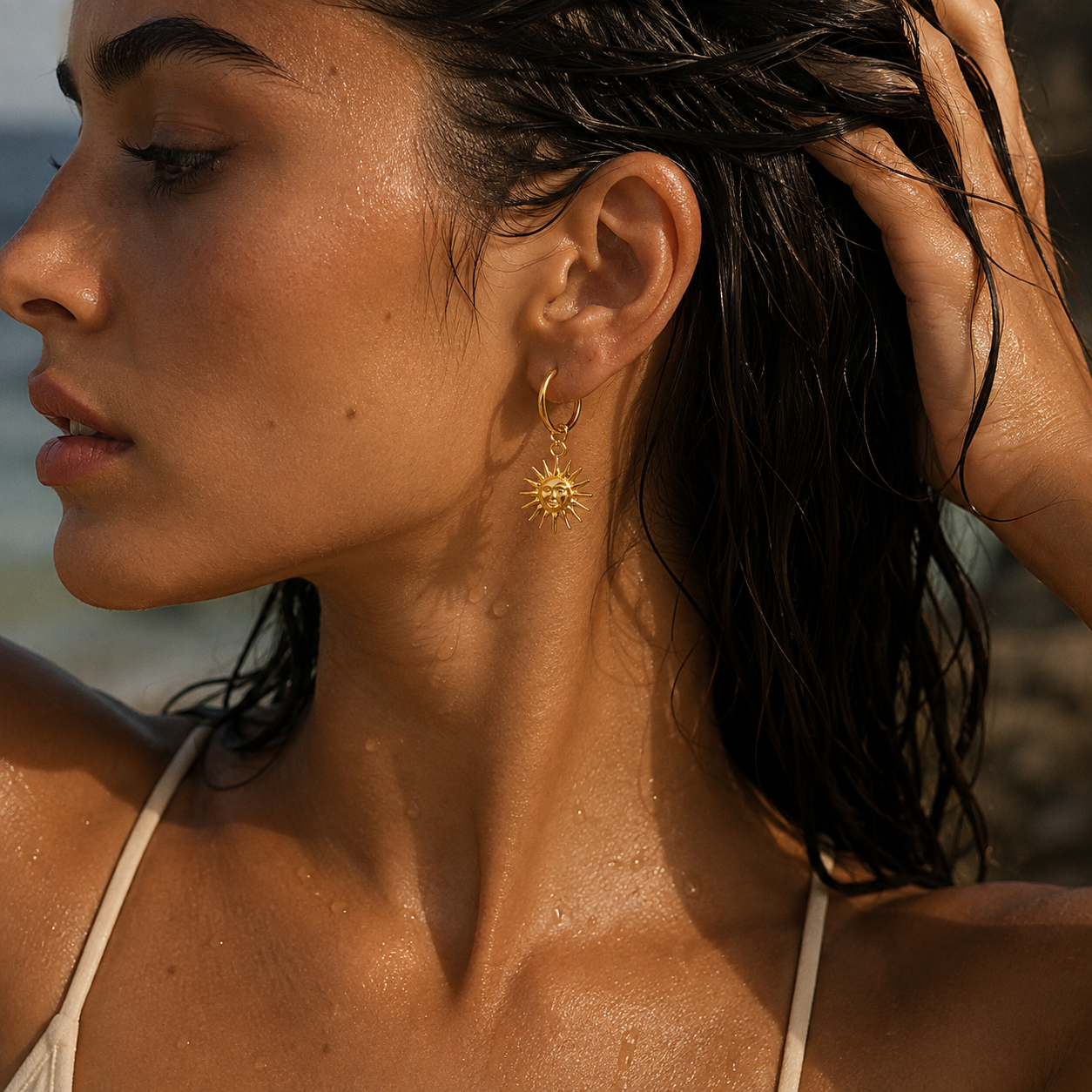 18K gold plated sun hoop earring worn by a woman at the beach