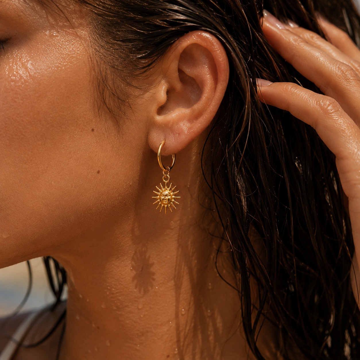     Gold sun hoop earring with celestial charm worn by a woman with wet hair
