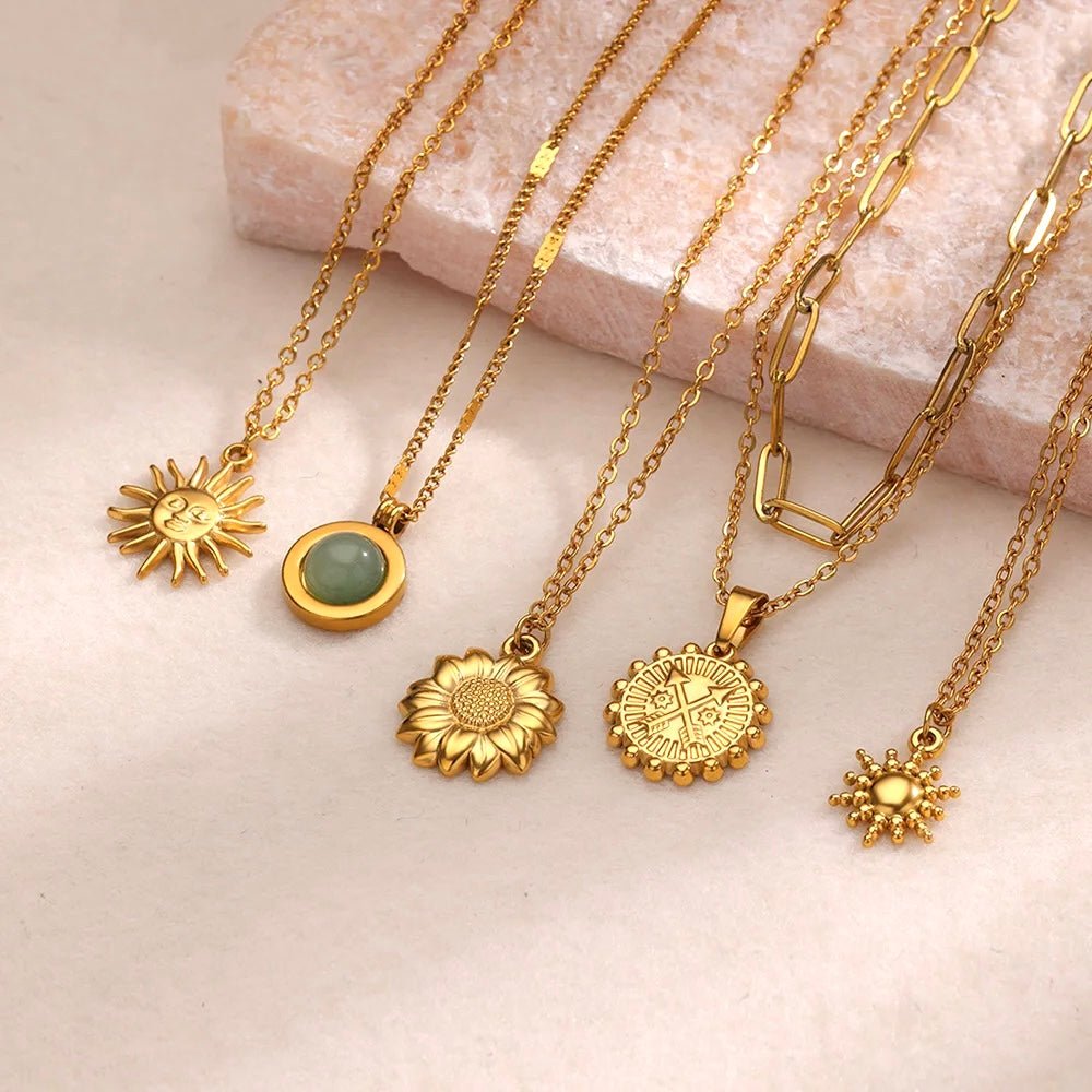 Multiple gold sun-themed pendant necklaces displayed on a glass stand