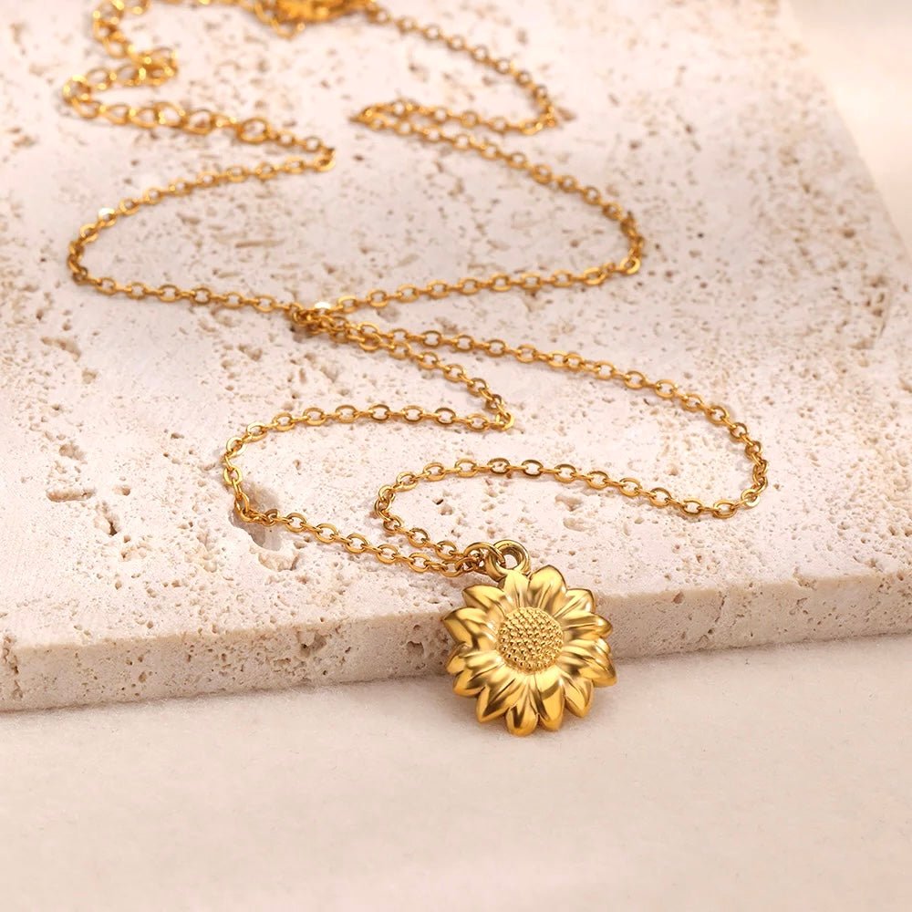 Gold sunflower charm necklace displayed on stone background