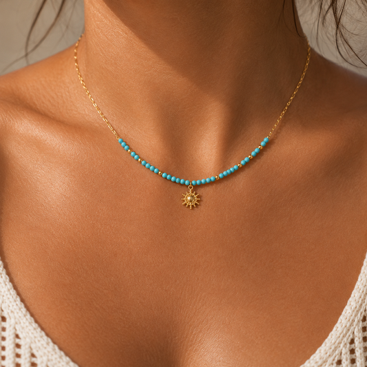 Close-up of Turquoise Sun Necklace with blue beads and gold sun charm worn on skin