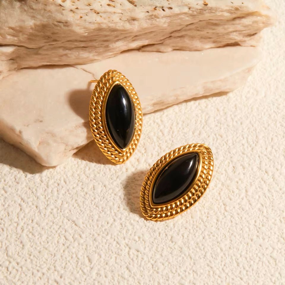 Close-up of retro marquise earrings with twisted gold frame and glossy black stone