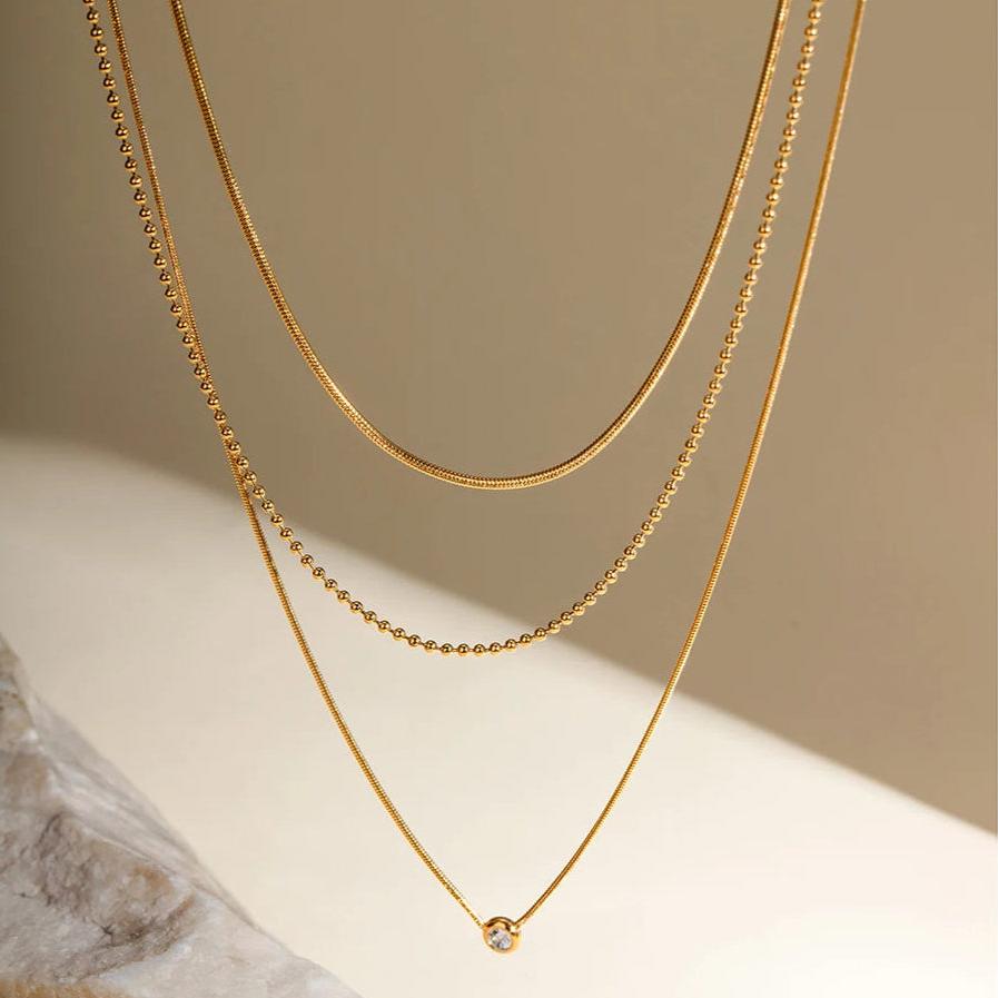 Close-up of a woman wearing the Zahia layered gold necklace with a solitaire pendant.