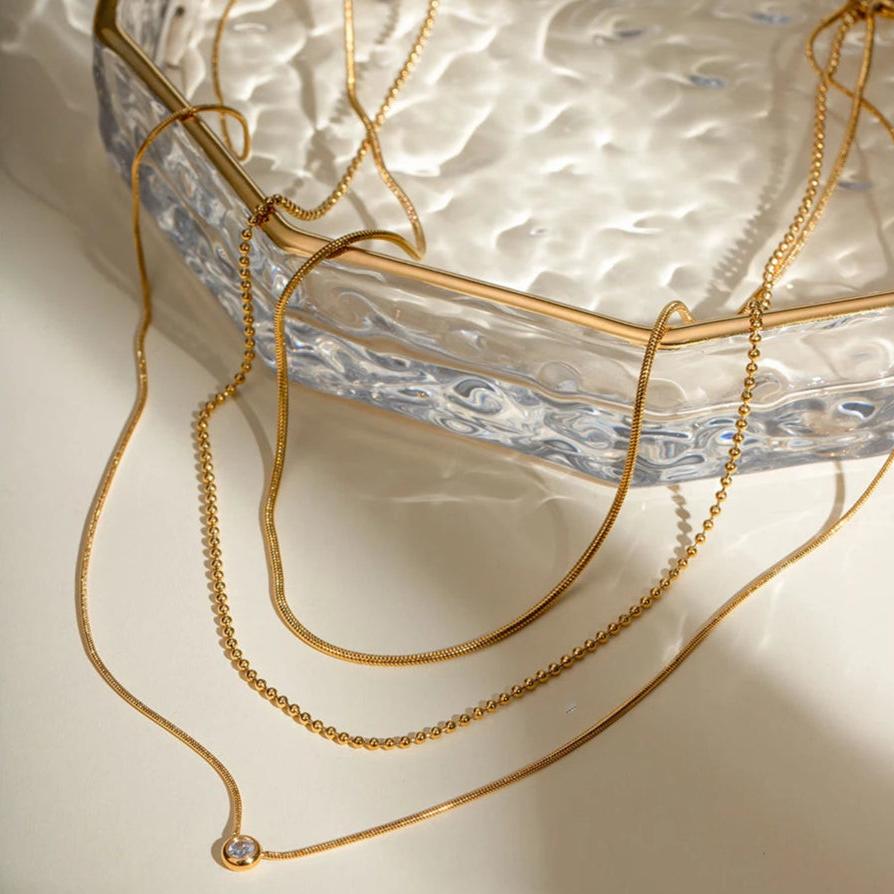 Zahia layered pendant necklace displayed on the edge of a wavy glass dish.
