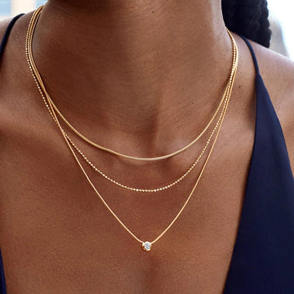 Close-up of a woman wearing the Zahia layered gold necklace with a solitaire pendant.